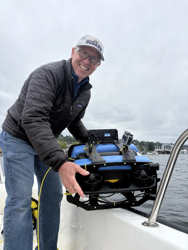 Captain George Spano lowering the ROV over the side of a boat on Lake Union